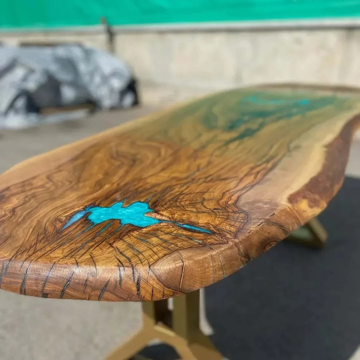 Original Atoll table in the workshop, live-edge hardwood with turquoise resin and gold legs