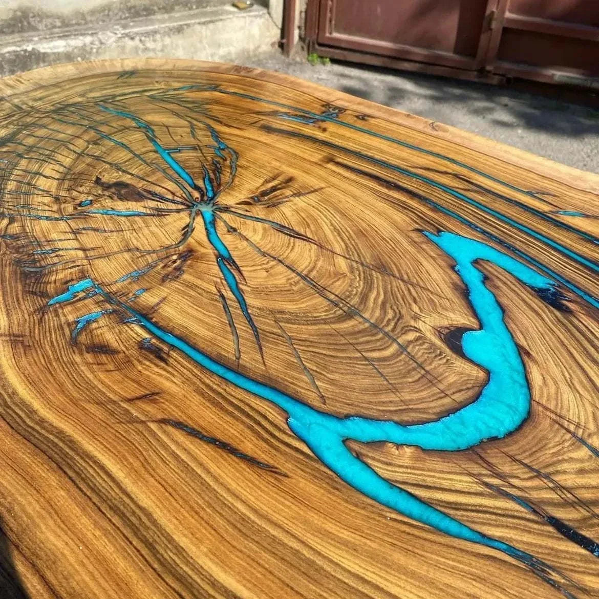 Turquoise epoxy resin filling the natural cracks of a live-edge hardwood slab